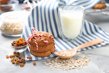 Delicious oatmeal cookies with raisins and glass of milk on table