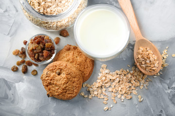 Delicious oatmeal cookies with raisins and glass of milk on table