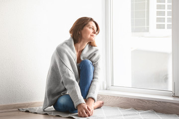 Depressed woman sitting near window at home