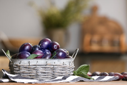 Fresh plums in wicker basket on table