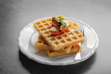Plate with delicious cinnamon waffles on grey background