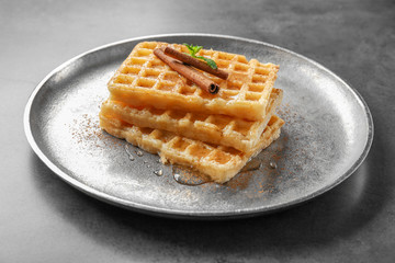 Metal plate with delicious cinnamon waffles on table
