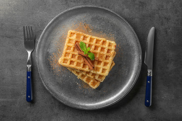 Metal plate with delicious cinnamon waffles on table