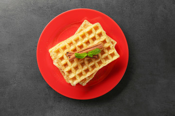 Plate with delicious cinnamon waffles on grey background