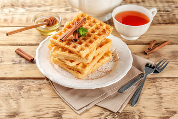 Plate with delicious cinnamon waffles on wooden table