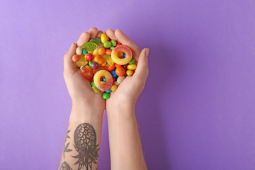 Woman holding colorful candies on violet background