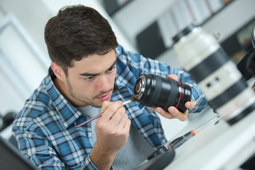 man cleaning lens of his digital camera with special brush
