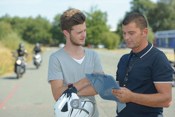 Young man talking to instructor of motorcycle training course