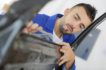 young coachbuilder mechanic straightening car door - obrazy, fototapety, plakaty