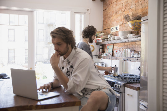 Young man using a laptop in his kitchen