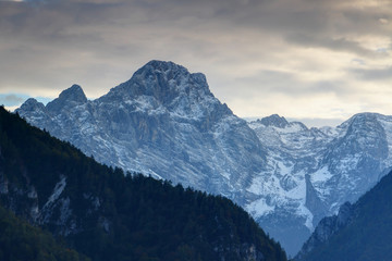 North face of snowy Rjavina peak towering above pine forests and ridges of Kot Valley at dusk, Triglav mountain group, Triglav National Park, Julian Alps, Slovenia, Europe