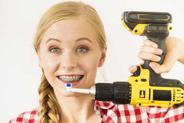 Woman with braces brushing teeth with drill