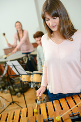 woman with other musicians playing a xylophone