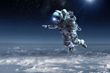 Obraz na płótnie Canvas Astronaut floating above clouds