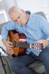 senior man at home learning to play guitar