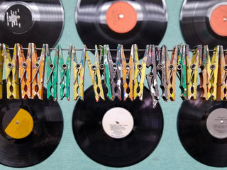 row of paint splattered clothespins on wire with retro black vinyl records
