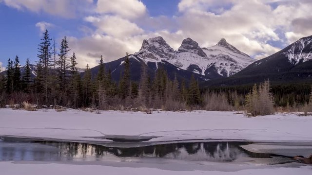 Sunset view of the Three Sisters from a frozen Policemen's Creek along the Bow River outside Canmore, Alberta in winter.