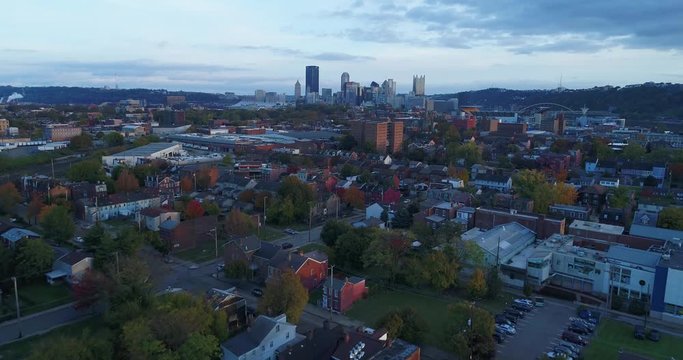 An evening reverse aerial establishing shot from a residential neighborhood with the Pittsburgh skyline in the distance. Shot at 48fps.	 	