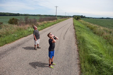 People looking at the sun during a solar eclipse on a country road
