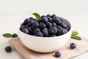 Juicy and fresh blueberries with green leaves on white bowl. Healthy eating