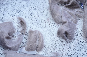 gray shirt soak in powder detergent water dissolution on black plastic basin