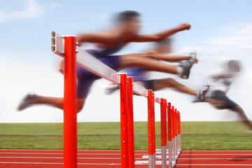 Hurdle race, men jumping over hurdles in a track and field race. Motion blurred image, digitally...