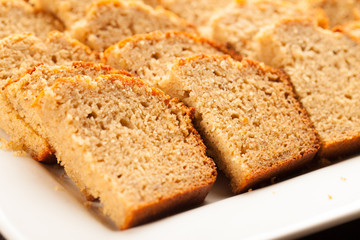 
Freshly baked pumpkin bread slices on white platter on dark wood background up close shot
