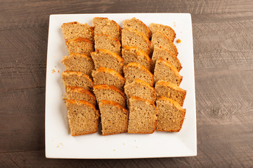 
Freshly baked pumpkin bread slices on white platter on dark wood background top view

