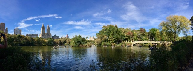 Fototapeta na wymiar Pond and Bow bridge at Central Park in early fall panorama view