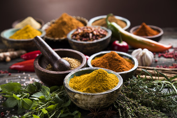 Various colorful spices on a wooden table in bowls