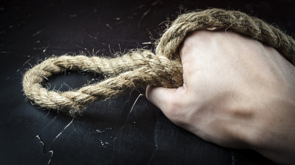 A man's hand holds a rope with a loop, the concept of self-sacrifice