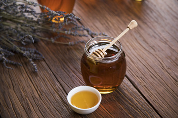 Honey in jar with honey dipper on wooden background 