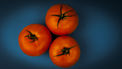 Three tomatoes on a blue background