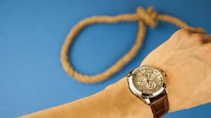 A man looks at the watch against the background of a rope with a loop