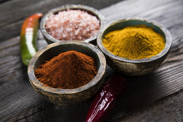 Various colorful spices on a wooden table in bowls