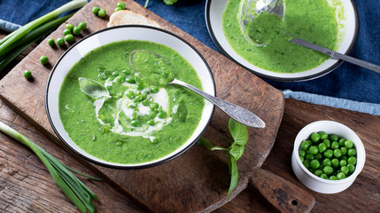 Green pea soup on wooden cutting board. Top view