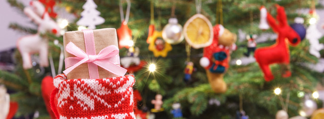 Gift for Christmas with red woolen sock, christmas tree with decoration, festive time concept
