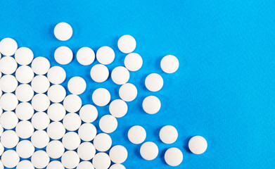 White pills on a blue background. Top view. Medical background.