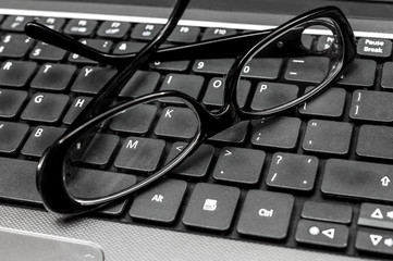 Glasses on the laptop's keyboard. Close up.