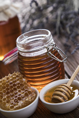Honey in jar with honey dipper on wooden background 