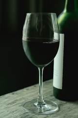 Wine in glass with bottle on brown wooden table.
