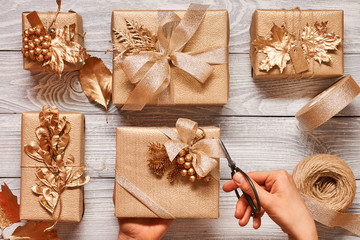 Woman wrapping christmas presents over wooden background