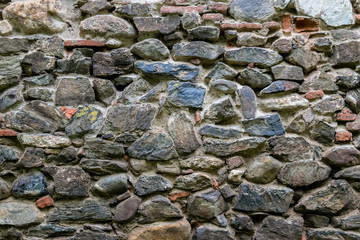 Medieval wall built of stone and bricks, background texture