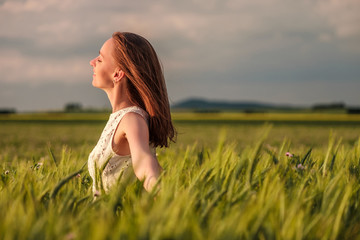 Beautiful woman in white dress on green wheat field