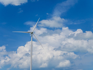 Wind turbine with blue sky and white clouds background.