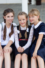 Schoolgirls in school uniform rest on a break near the school
