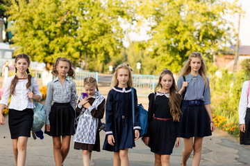 Obraz premium A group of schoolgirls with backpacks go to school