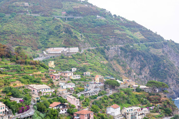 Naklejka premium View to city buildings and mountains in a foggy day. Riomaggiore, Italy