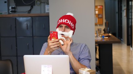 Funny Hipster Santa Businessman Wishing Merry Christmas Using Smartphone In Office. 4K. 