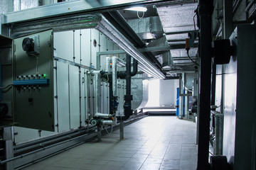 Side view of the huge gray industrial air handling unit in the ventilation plant room